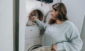 Žena dává prádlo do sušičky