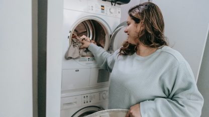 Žena dává prádlo do sušičky